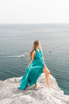 Woman sea green dress. Side view a happy woman with long hair in a long mint dress posing on a beach with calm sea bokeh lights on sunny day. Girl on the nature on blue sky background