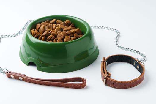 Green plastic bowl with dry pet food isolated on white background