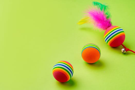 Colorful pet toys balls on green background close up