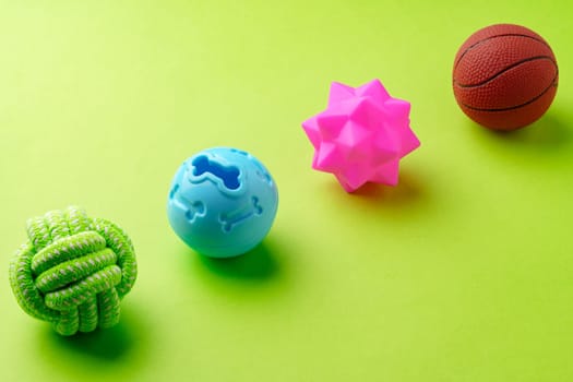 Colorful pet toys balls on green background close up