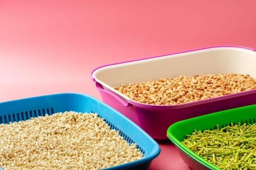 Pet litter box with bio filler on pink background close up