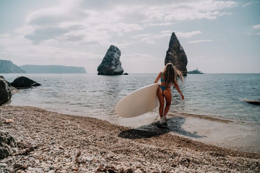 Close up shot of beautiful young caucasian woman with black hair and freckles looking at camera and smiling. Cute woman portrait in a pink bikini posing on a volcanic rock high above the sea