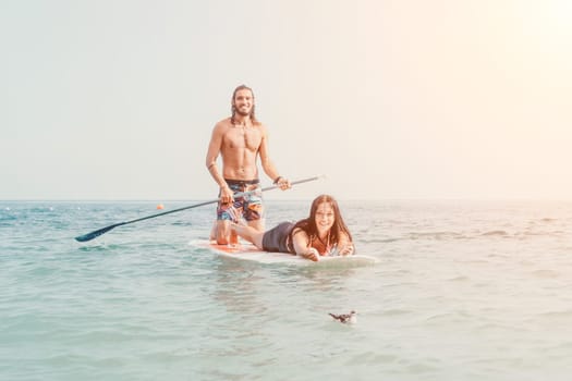 Silhouette of woman standing, surfing on SUP board, confident paddling through water surface. Idyllic sunset or sunrise. Sports active lifestyle at sea or river.