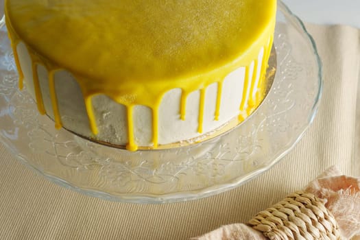 Cake sits elegantly on a glass stand, adorned with a glistening lemon glaze