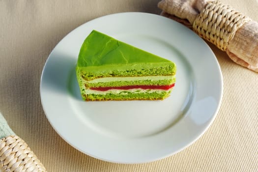 Showcasing a delectable piece of green cake on a pristine white plate, tempting the viewer