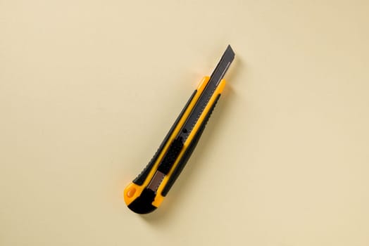 Utility knife with yellow and black handle on a yellow background