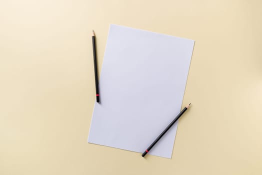 Blank white paper and black pencil on yellow background