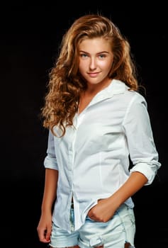 Portrait beautiful young brunette woman with wavy hair in white clothes, looking at the camera, isolated on dark background