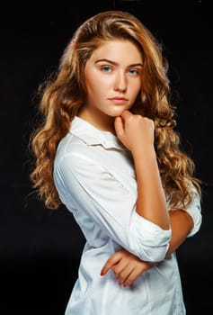 Portrait beautiful young brunette woman with wavy hair in white clothes, looking at the camera, isolated on dark background