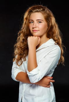 Portrait beautiful young brunette woman with wavy hair in white clothes, looking at the camera, isolated on dark background