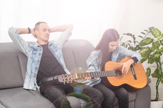 Artistic talented girl showing her latin music teacher the new song she learned to play on the acoustic guitar at home. High quality photo