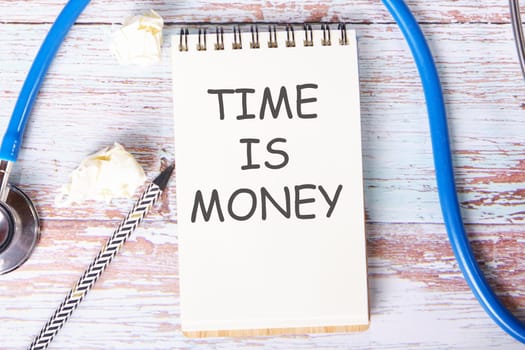 TIME IS MONEY text is written on a notebook that lies on old vintage boards