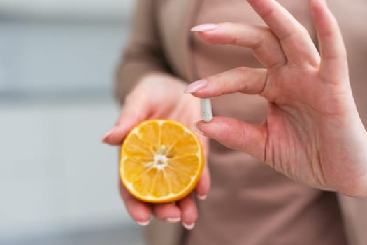 pills in one hand and an orange in the other. High quality photo