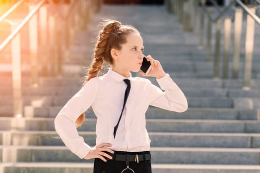 Young schoolgirl in white classical blouse posing in the city