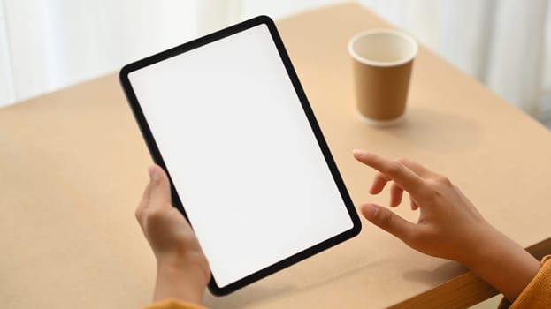 Woman hand holding digital tablet with white blank screen for advertisement. Close up view.