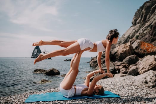 Woman sea yoga. Back view of free calm happy satisfied woman with long hair standing on top rock with yoga position against of sky by the sea. Healthy lifestyle outdoors in nature, fitness concept.