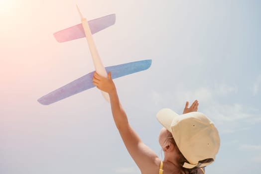 Kid playing with toy airplane. Children dream of travel by plane. Happy child girl has fun in summer vacation by sea and mountains. Outdoors activities at background of blue sky. Lifestyle moment