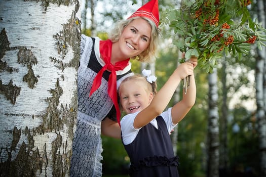 Young and adult schoolgirl on September 1, mother and daughter having fun and joy. Generations of schoolchildren of USSR and Russia. Female pioneer in red tie and October girl in modern uniform