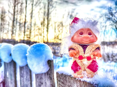 Cute little funny dwarf in the snow in the landscape in winter. Wizard on a snowy background. Christmas and New Year