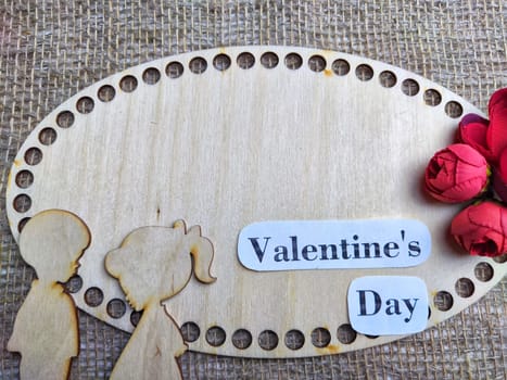 Wooden figurines of couple, inscription Valentine's Day, red flowers. Concept of holiday of love. Background, texture, frame, place for text, copy space