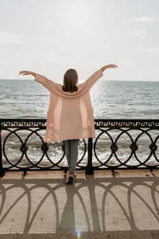 Woman travel sea. Young Happy woman in a long red dress posing on a beach near the sea on background of volcanic rocks, like in Iceland, sharing travel adventure journey