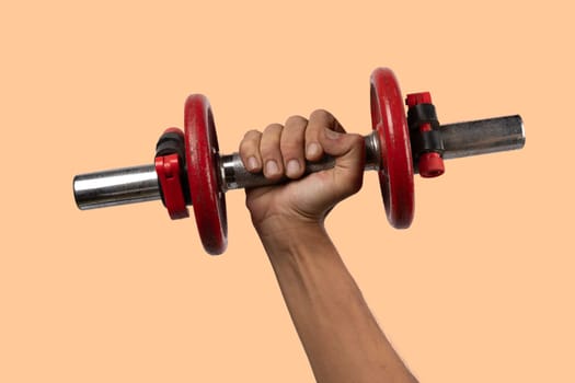 Black male hand holding an old dumbbell isolated on salmon background. High quality photo