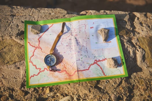 Still life. View from above of a compass lying on a map on the cliff, orienteering on the ground, a magnetic arrow points north, navigation in the seacoast. Navigational equipment. Tourism concept