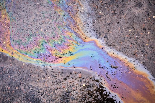 Textured stain of fuel or oil on wet asphalt on a rainy day.