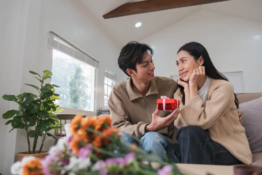 Asian couple affectionately hugging their lover, giving gifts, giving a surprise on Valentine's Day. home interior decoration.