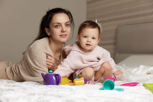 mother and cute little child daughter playing tea party and spending time together in bedroom