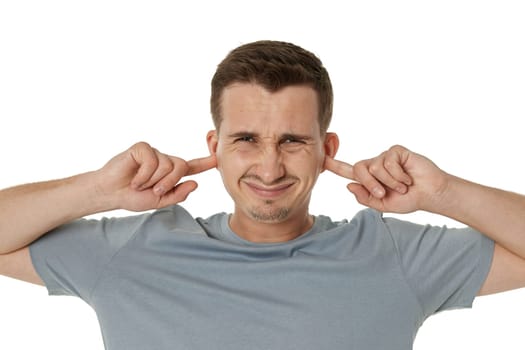 Young annoyed caucasian man in t-shirt closed eyes cover ears with hands fingers on white background