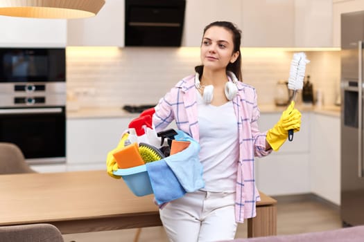 Woman in rubber protective yellow gloves holding cleaning tools. house chores.
