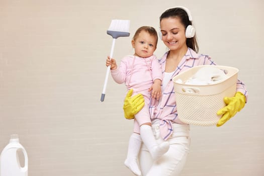 happy mother housewife is holding cute baby girl and basket with laundry , Happy family, copy space