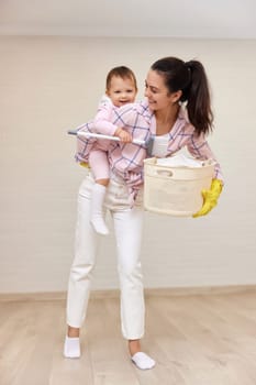 happy mother housewife is holding cute baby girl and basket with laundry , Happy family