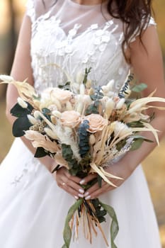 hands of the bride holding beautiful autumn bouquet outdoor