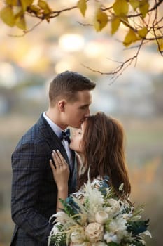 beautiful sensual bride in white wedding dress and groom standing outdoor on natural background