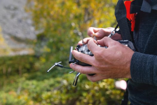 male hands holding sticks on the remote control of a drone, close-up, outdoors.