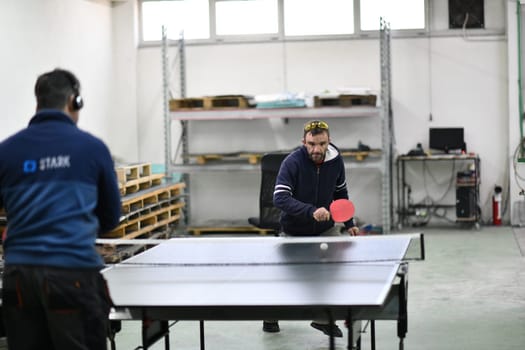 group of industry workers playing ping pong or table tennis game and relaxing in their free time at modern creative metal industry production factory