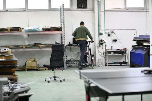 worker or technician engineer in an electronic repair shop workshop rides electric scooter in a factory