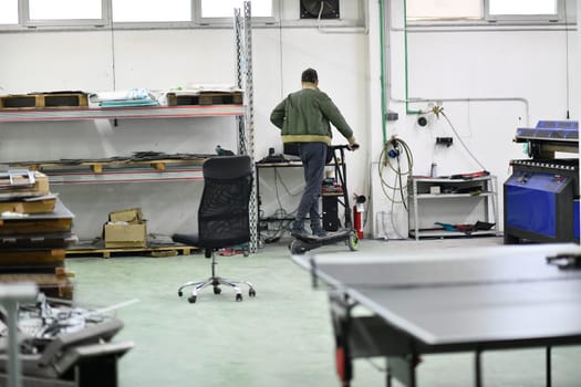 worker or technician engineer in an electronic repair shop workshop rides electric scooter in a factory