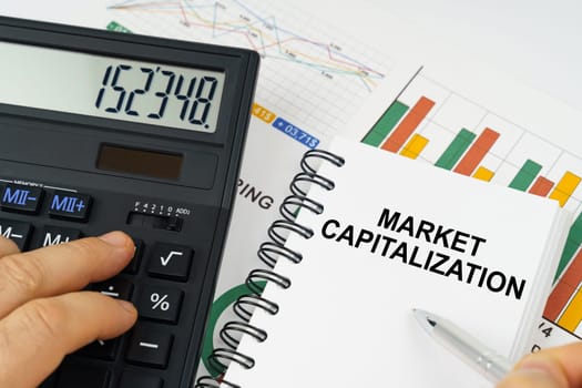 Business concept. On the table there is a calculator, reports with graphs and a notepad with the inscription - Market capitalization