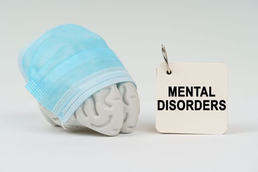 Medical concept. On a white surface next to the brain there is a notepad with the inscription - mental disorders