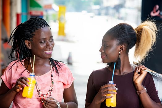 girls shopping with bottles of juice in hand and looking at each other smiling.