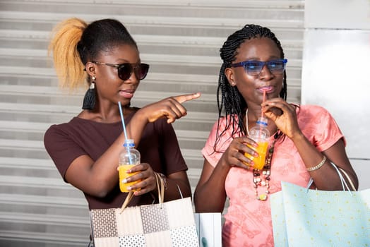 young girl standing in sunglasses showing something with fruit juice bottles in hand after shopping.