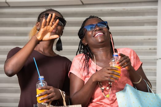 Young girls standing in glasses looking up laughing with bottles of juice in hand after shopping.