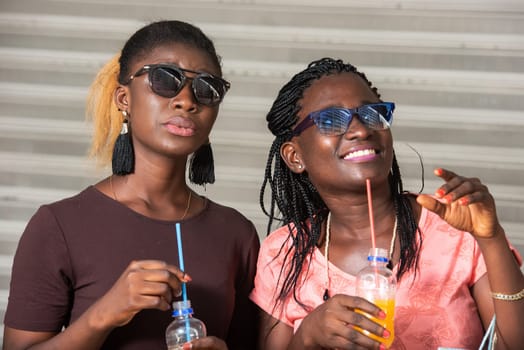 Young girls standing in glasses looking up laughing with bottles of juice in hand after shopping.