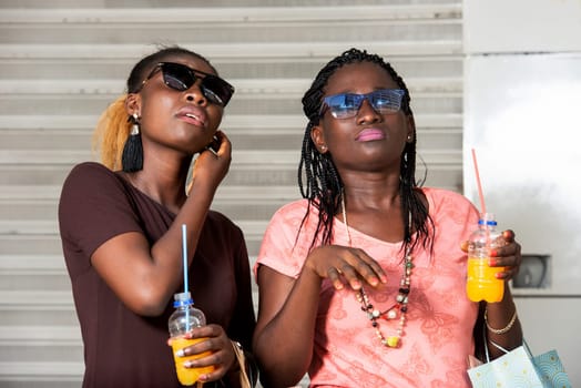 Young girls standing in glasses looking up there with bottles of juice in hand after shopping.