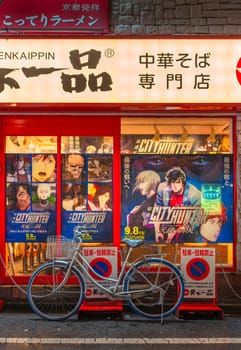 tokyo, shinjuku - sep 08 2023: Bike parked illegally aside a Chinese Soba restaurant facade adorned with posters of the Japanese anime Angel Dust adapted from the manga City Hunter aka Nicky Larson.
