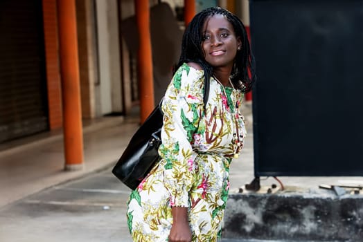 young african woman standing outdoors looking at camera smiling.