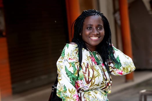 young african woman standing outdoors looking at camera smiling.